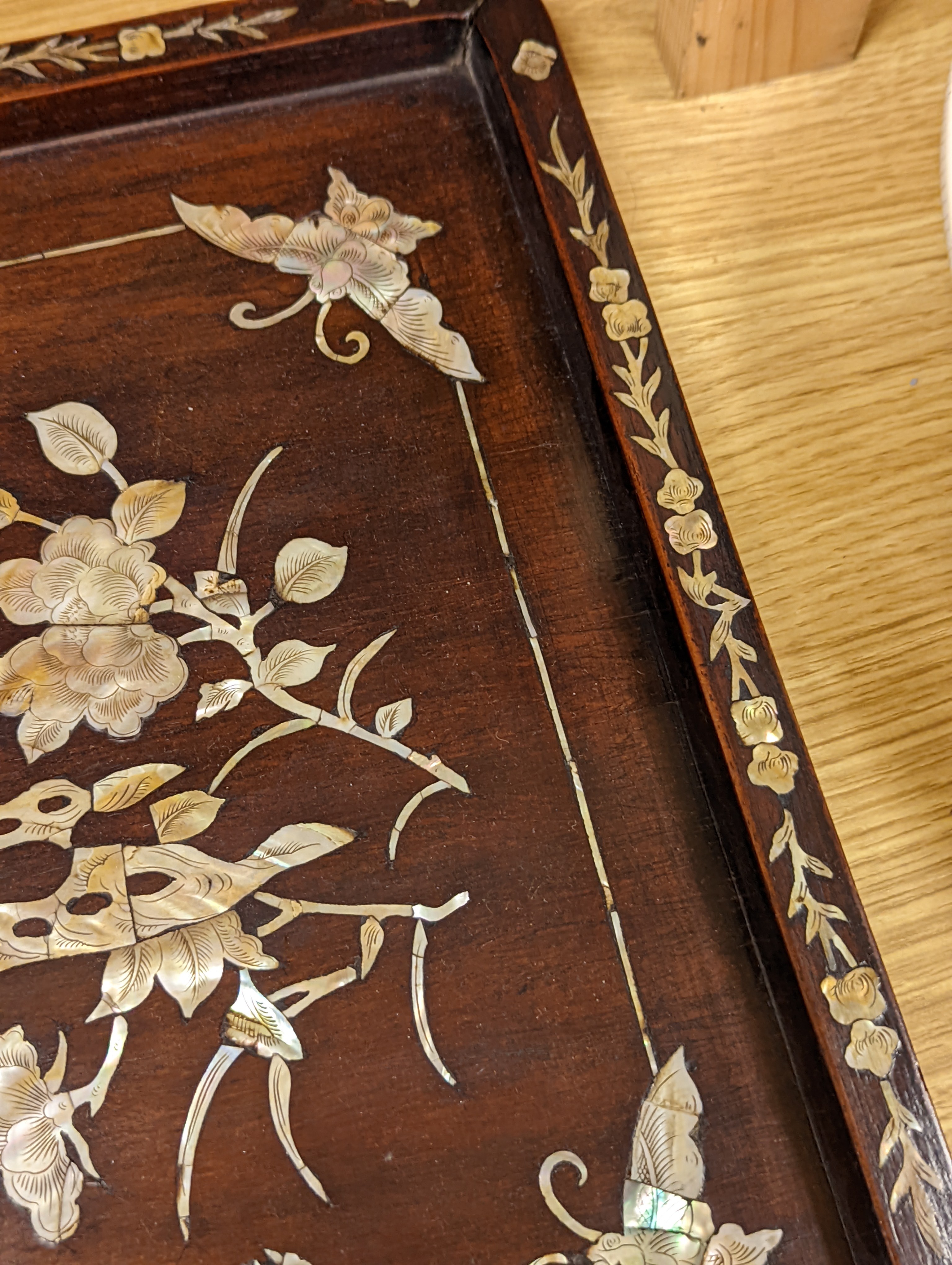 Two Chinese mother of pearl inlaid hongmu trays, the rectangular example with birds and insects amid flowers and the smaller oval example with a pavilion in a landscape within floral sprays 55x34cm